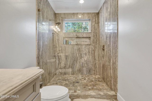 bathroom with ornamental molding, vanity, toilet, and a tile shower