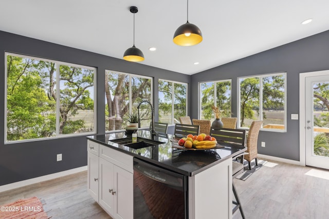 kitchen with white cabinets, dishwasher, baseboards, and a sink
