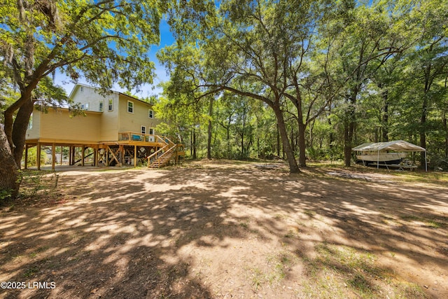 view of yard featuring dirt driveway, stairway, and a carport