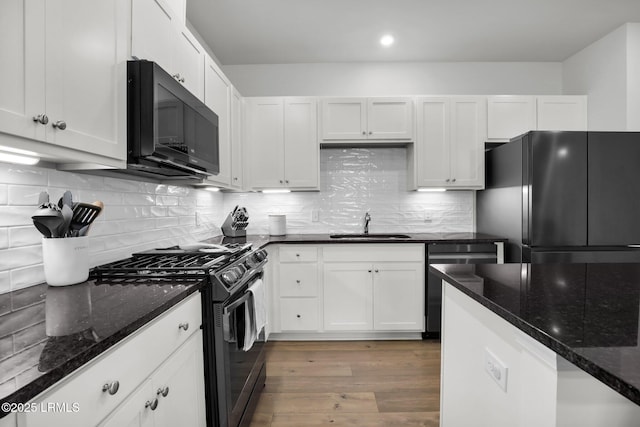 kitchen featuring white cabinetry, dark stone countertops, black refrigerator, range with gas stovetop, and dishwasher