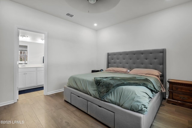 bedroom with ceiling fan, ensuite bath, and hardwood / wood-style floors