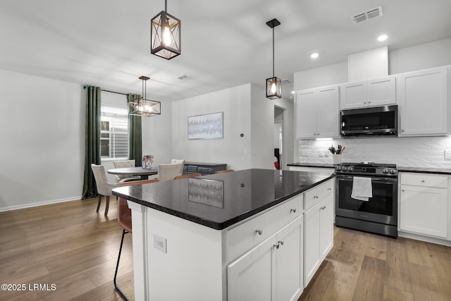 kitchen with a kitchen island, white cabinetry, appliances with stainless steel finishes, and pendant lighting