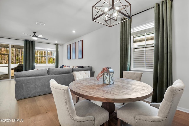 dining room featuring ceiling fan with notable chandelier and light wood-type flooring