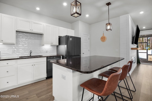 kitchen with sink, black fridge, a center island, stainless steel dishwasher, and pendant lighting