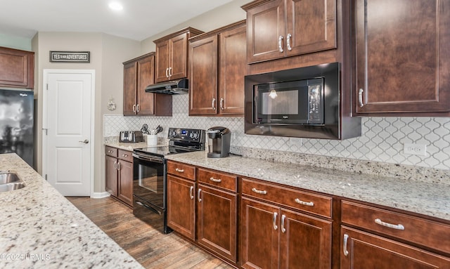 kitchen featuring sink, dark wood-type flooring, light stone countertops, black appliances, and decorative backsplash