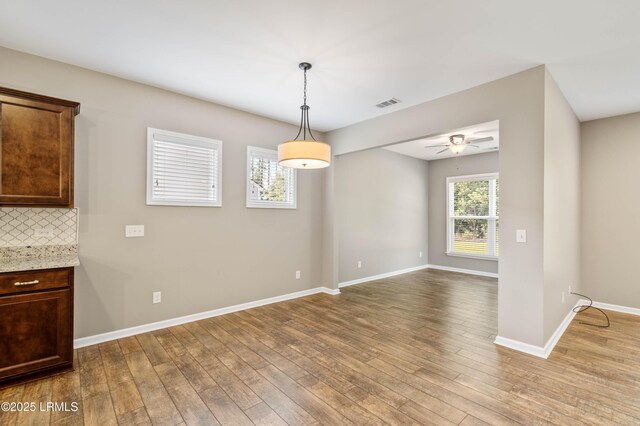 59 Gatewood Ln, Bluffton, SC 29910 - kitchen with black appliances, hardwood / wood-style floors, backsplash, under cabinet range hood, and an island with sink
