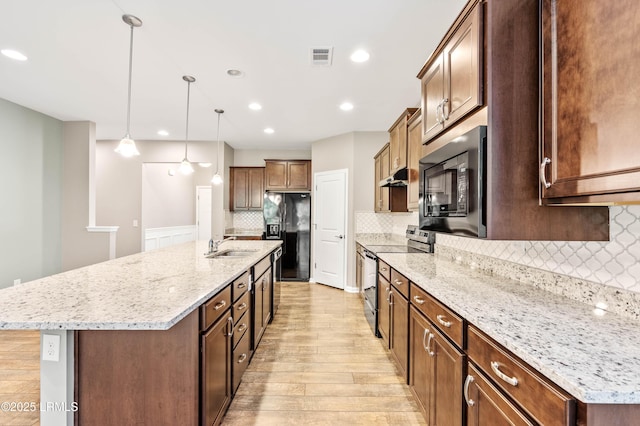 59 Gatewood Ln, Bluffton, SC 29910 - kitchen featuring black appliances, light wood finished floors, under cabinet range hood, tasteful backsplash, and a kitchen island with sink