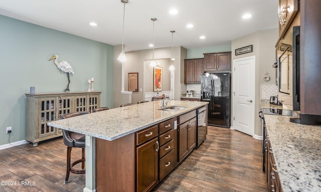 kitchen featuring sink, a kitchen island with sink, light stone counters, decorative backsplash, and black refrigerator with ice dispenser