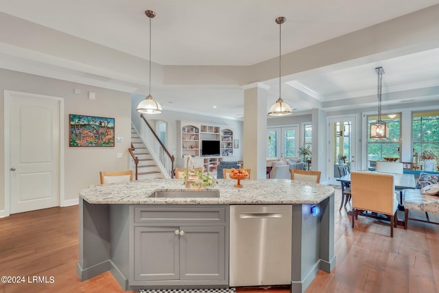 kitchen featuring pendant lighting, a kitchen island with sink, sink, and dishwasher