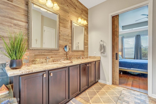 bathroom with ceiling fan, vanity, and wooden walls