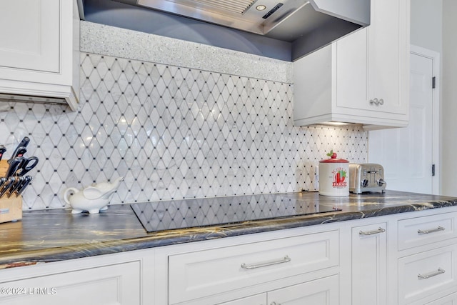 kitchen featuring tasteful backsplash, white cabinets, black electric stovetop, and wall chimney range hood