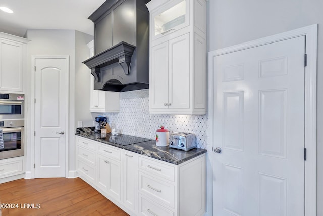 kitchen with white cabinetry, custom range hood, and black electric cooktop