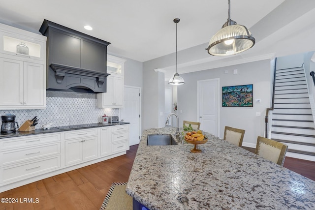 kitchen with sink, tasteful backsplash, white cabinets, black electric cooktop, and decorative light fixtures