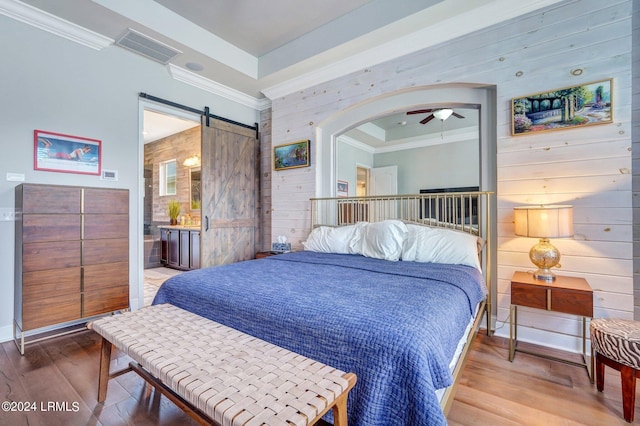 bedroom featuring wood-type flooring, a barn door, ornamental molding, and wood walls