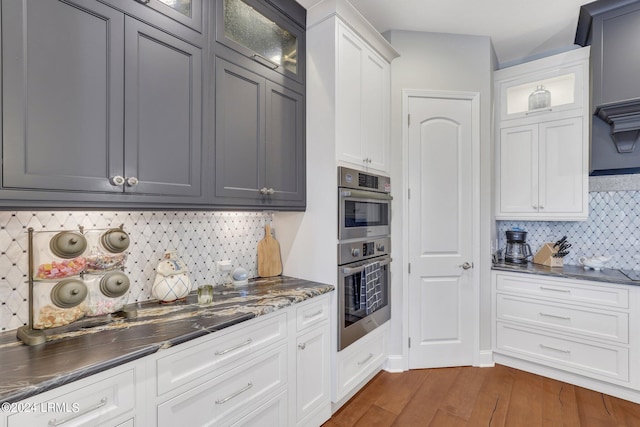 kitchen featuring white cabinetry, dark hardwood / wood-style flooring, double oven, and decorative backsplash