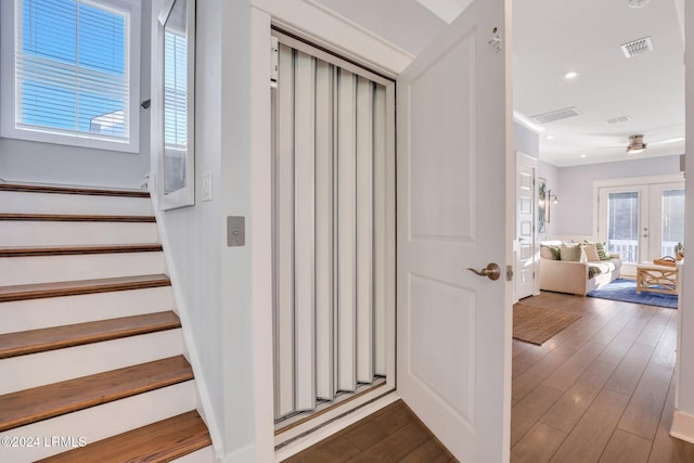 stairs with hardwood / wood-style floors and french doors