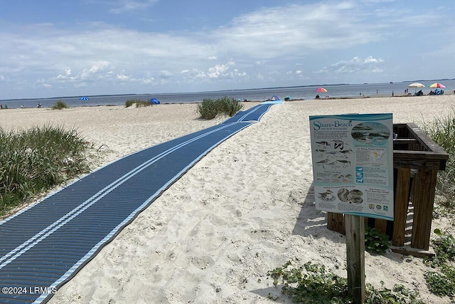 view of property's community with a water view and a beach view