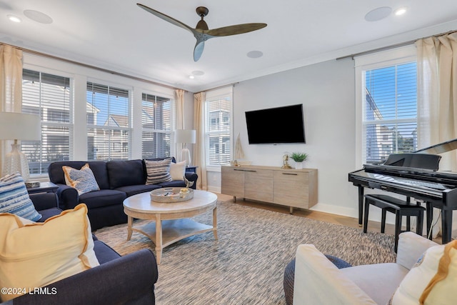 living room featuring crown molding, ceiling fan, a healthy amount of sunlight, and light hardwood / wood-style flooring