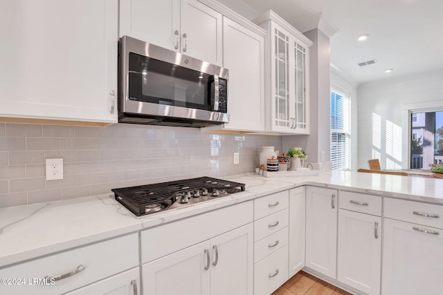 kitchen featuring white cabinetry, stainless steel appliances, tasteful backsplash, light stone counters, and light hardwood / wood-style floors