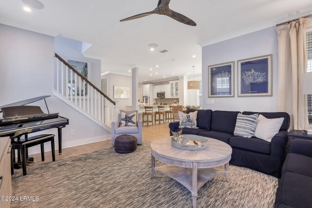 living room with ceiling fan, ornamental molding, and light hardwood / wood-style floors