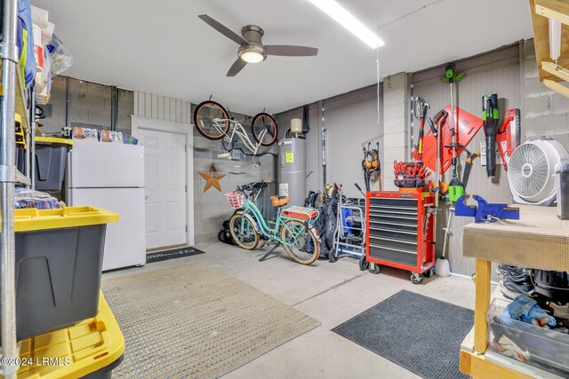 garage with water heater, ceiling fan, white refrigerator, and a workshop area