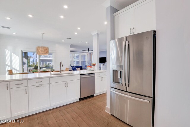 kitchen with white cabinetry, appliances with stainless steel finishes, decorative light fixtures, and sink