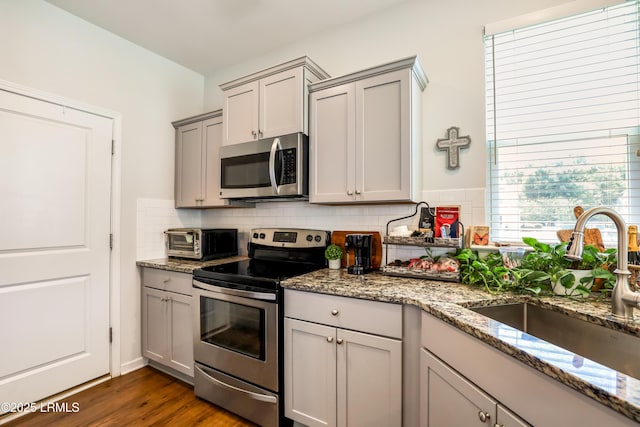 83 Plumgrass St, Bluffton, SC 29910 - kitchen with stainless steel appliances, gray cabinetry, backsplash, light stone countertops, and dark wood-style floors