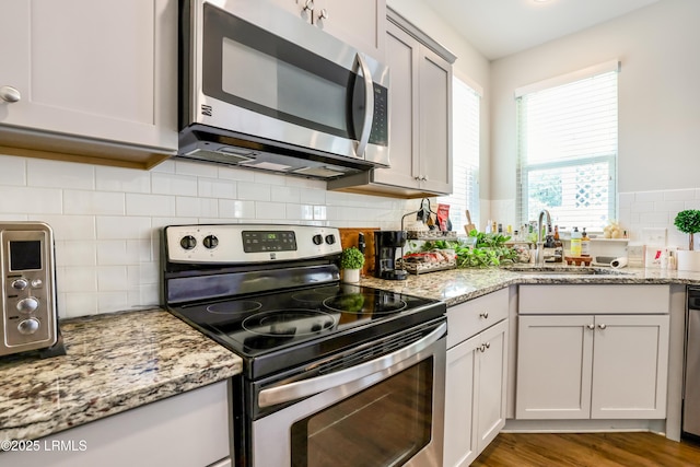 83 Plumgrass St, Bluffton, SC 29910 - kitchen featuring stainless steel appliances, backsplash, light stone countertops, and wood finished floors