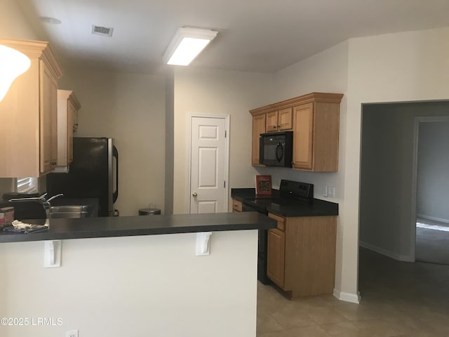 kitchen featuring visible vents, dark countertops, light tile patterned floors, black appliances, and a peninsula