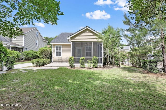 rear view of house with a lawn, a shingled roof, a sunroom, and a patio area