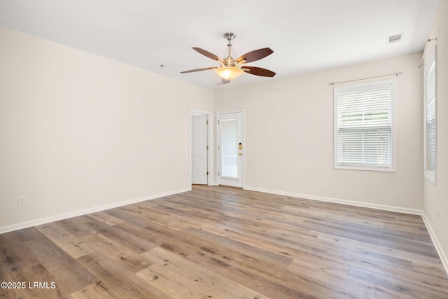 unfurnished room featuring baseboards, ceiling fan, visible vents, and wood finished floors