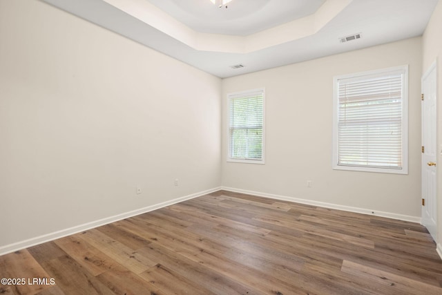 spare room with visible vents, baseboards, and wood finished floors