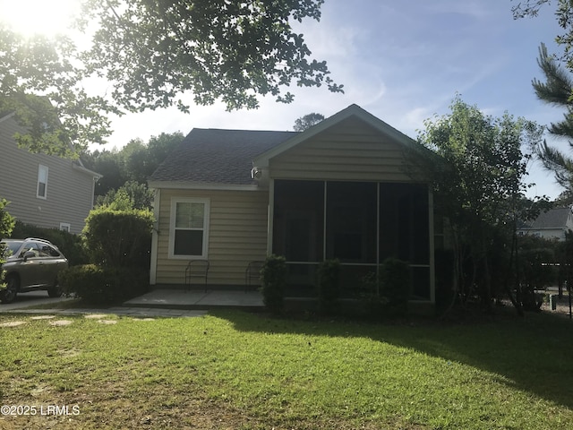 back of property featuring a lawn, roof with shingles, and a sunroom