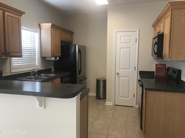 kitchen with black microwave, dark countertops, a sink, a peninsula, and electric stove