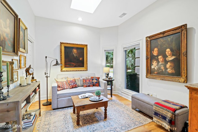 living room featuring a skylight, baseboards, visible vents, light wood-type flooring, and recessed lighting