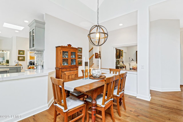 dining space with light wood finished floors, a skylight, baseboards, stairway, and recessed lighting