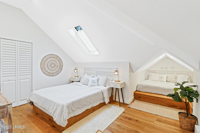 bedroom with light wood-type flooring and lofted ceiling with skylight