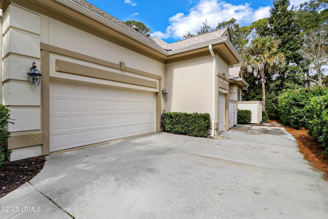 view of side of property featuring a garage, concrete driveway, and stucco siding