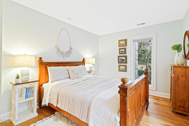 bedroom featuring light wood-style floors, visible vents, and baseboards