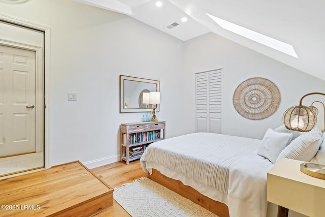 bedroom with vaulted ceiling with skylight, baseboards, visible vents, wood finished floors, and recessed lighting