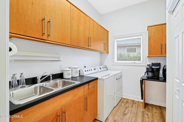 washroom featuring washer and dryer, cabinet space, a sink, light wood-type flooring, and baseboards