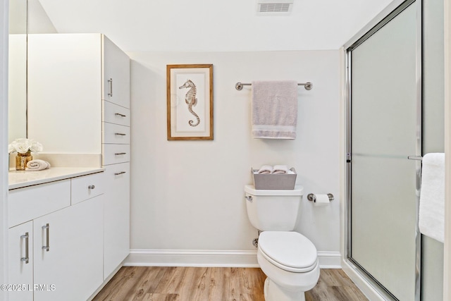 bathroom featuring toilet, wood finished floors, vanity, visible vents, and baseboards