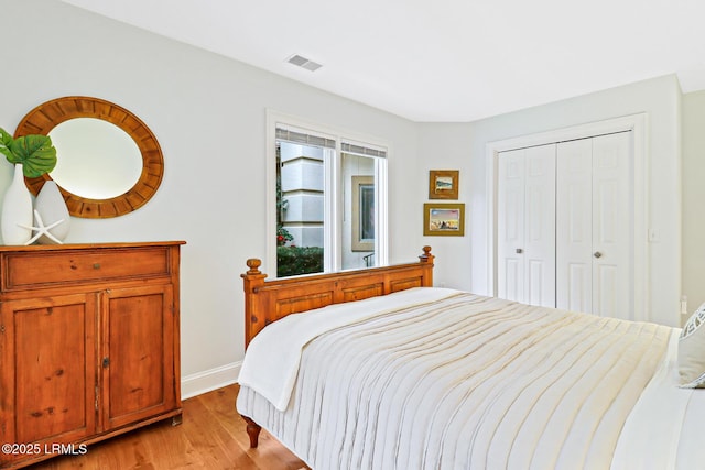 bedroom with light wood-type flooring, a closet, visible vents, and baseboards