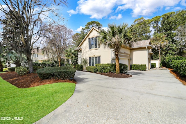 view of front of house with a garage, a front yard, driveway, and stucco siding