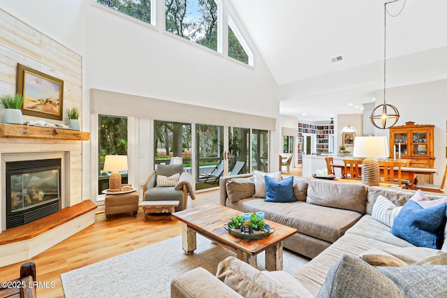 living area featuring a large fireplace, a high ceiling, visible vents, and wood finished floors