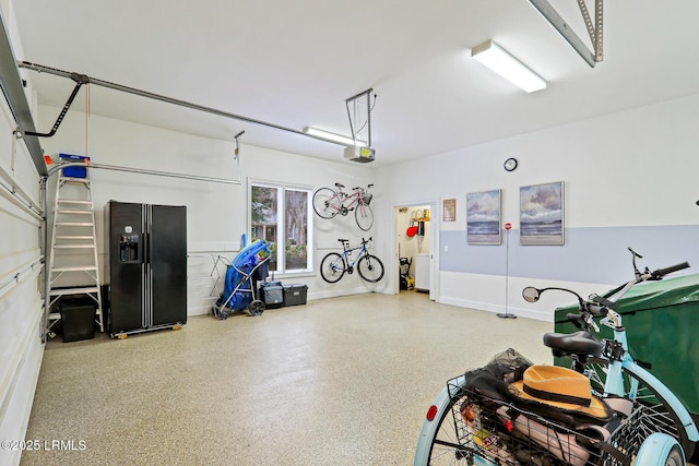 garage featuring baseboards, black fridge, and a garage door opener