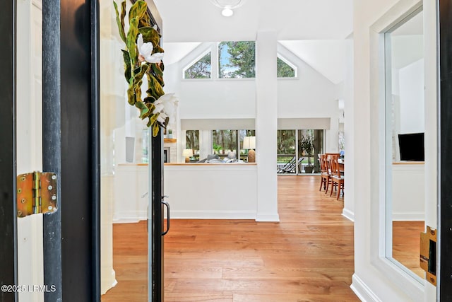 entryway with high vaulted ceiling, light wood-style flooring, and baseboards