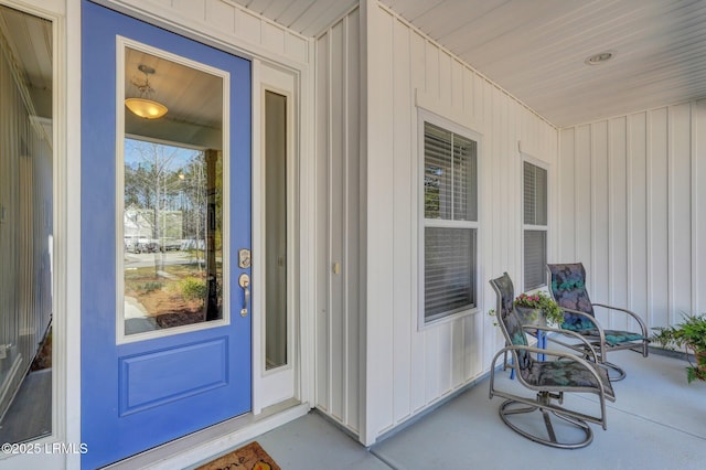 view of exterior entry with covered porch and board and batten siding