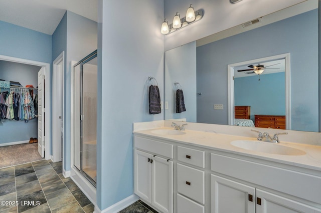 full bath featuring double vanity, a shower stall, a spacious closet, and a sink