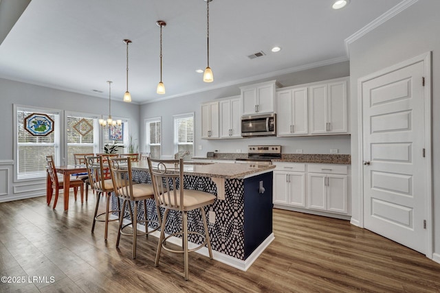 kitchen with a breakfast bar area, appliances with stainless steel finishes, a kitchen island, and dark wood-style flooring